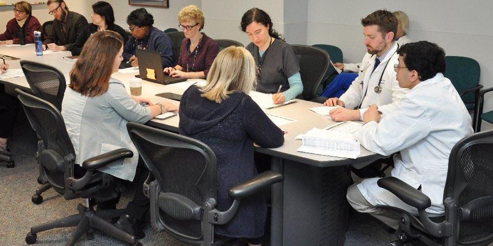 Doctors, occupational therapists, physical therapists, speech therapists, recreational therapists, rehab counselors, and other medical professionals in rehabilitation medicine are sitting around a table.